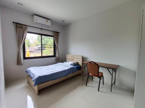 Ban Phlu YaiSino Village的一间卧室配有一张床、一张书桌和一个窗户。