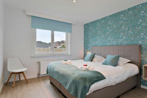 米德尔克尔克Bright and spacious bungalow with garden near the beach的一间卧室设有一张蓝色墙壁的大床