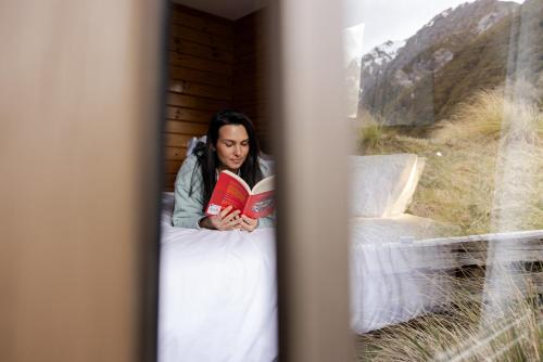 库克山村Haka House Aoraki Mt Cook的躺在床上读书的女人