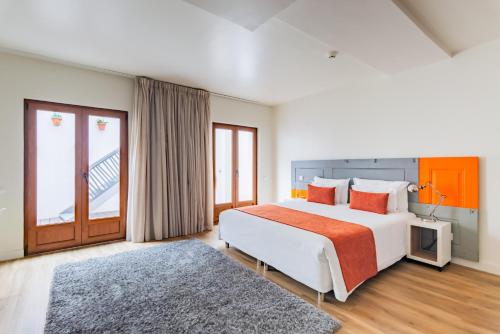帕尔梅拉Porta da Arrábida Suites的一间卧室配有一张大床和电视