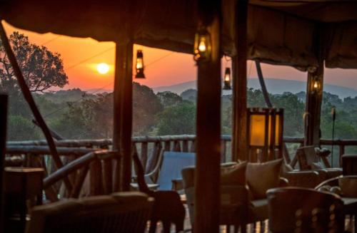 Sekenanisunshine maasai Mara safari camp in Kenya的餐厅的椅子享有日落美景