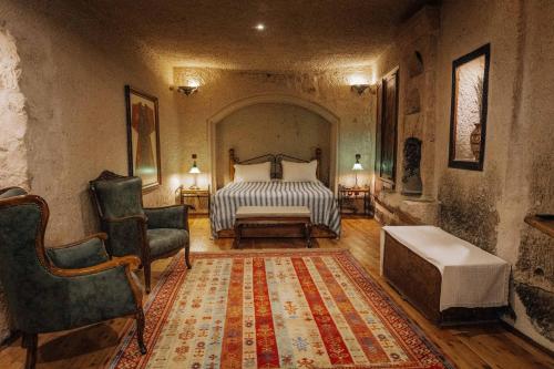 格雷梅Aza Cave Cappadocia Adult Hotel的一间卧室配有一张床、一把椅子和地毯