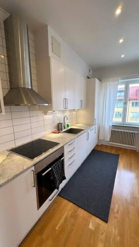 哥德堡Luxurious And Spacious Apartment的厨房配有白色橱柜和黑炉灶烤箱。