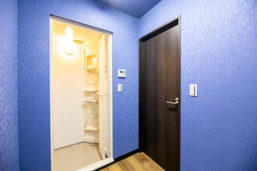 大阪Cote House的一间蓝色的房间,设有门和空冰箱