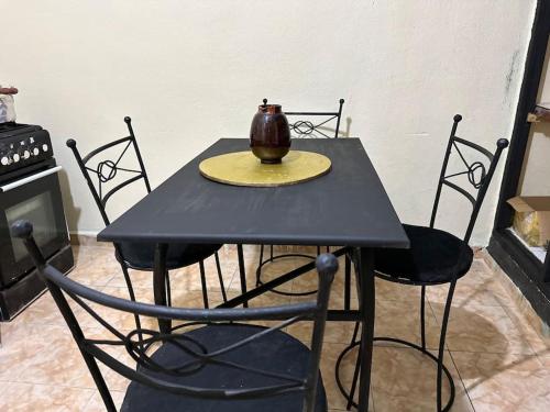 马拉喀什Appartement à côté de l'aéroport的一张带椅子的黑桌子和一个花瓶