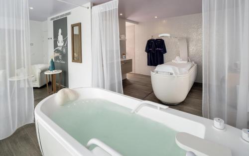 波尔尼谢Hôtel Château des Tourelles, Thalasso et piscine d'eau de mer chauffée的白色的浴室设有浴缸和水槽。