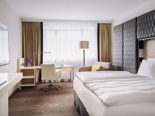 柏林铂尔曼柏林施维泽霍夫酒店的配有一张床和一张书桌的酒店客房