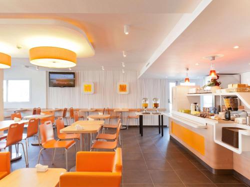 维也纳宜必思维也纳会展中心快捷酒店的一间设有橙色桌椅的餐厅和一间酒吧