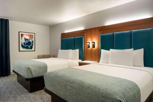 威廉斯堡Wingate by Wyndham Williamsburg的两张位于酒店客房的床,配有蓝色窗帘