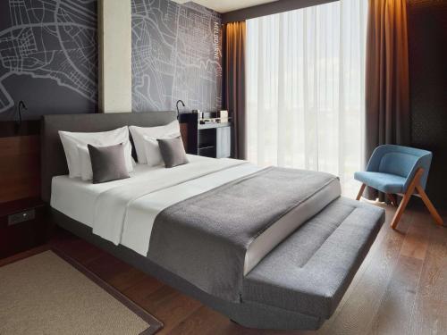 萨格勒布Mövenpick Zagreb的一间卧室配有一张大床和一张蓝色椅子
