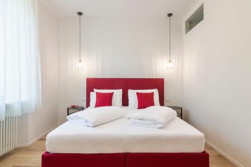 特伦托Electric Rooms & Suites的一张带红色和白色枕头的床和红色床头板