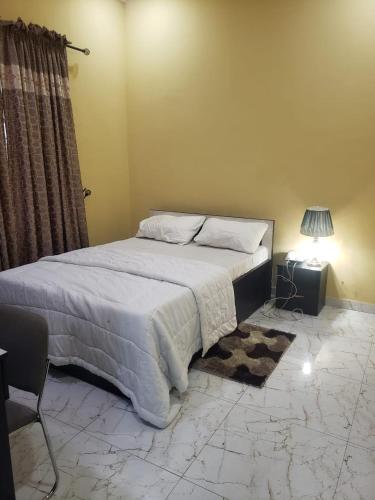 拉各斯Truth Key Hotel & Suites的一间卧室配有一张床、一张桌子和一盏灯