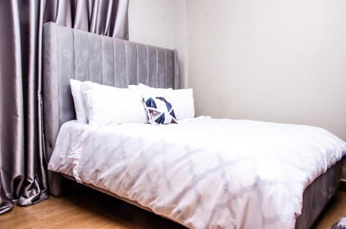 ThikaKeisha Homes的一张带白色床单和灰色床头板的床