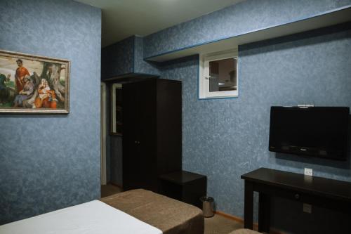 巴库Address Boutique Hotel Baku的卧室设有蓝色的墙壁、一张床和一台平面电视。