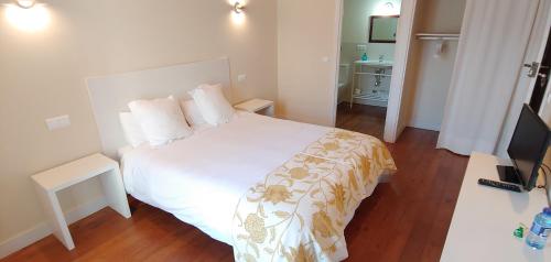 CamponarayaHostal Camponaraya的卧室配有白色的床和电视。