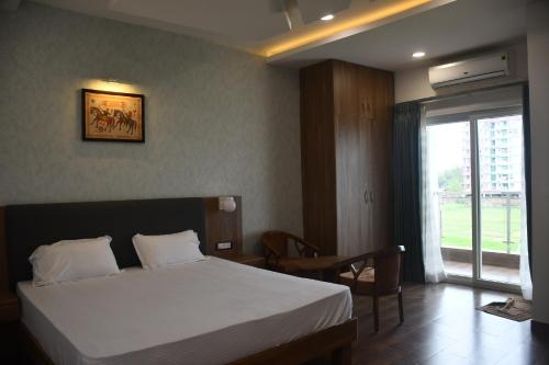 加雅Vatika Banquet And Lawn的一间卧室配有一张床、一张桌子和一个窗户。