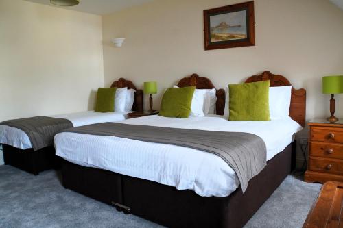 圣赫利尔泽西莫文酒店之高地公寓的配有绿色枕头的酒店客房内的两张床