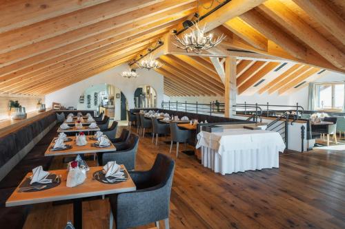 瑙德斯Bergresort Das Jochelius的用餐室设有桌椅和木制天花板