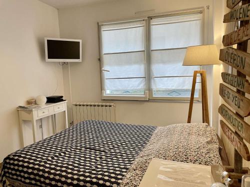 诺亚芒提亚Appartement Noirmoutier-en-l'Île, 1 pièce, 2 personnes - FR-1-224B-146的一间卧室设有一张床、一台电视和一个窗口。