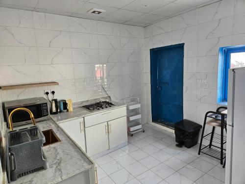 Ḩajlahمنزل حجري بحديقتين的厨房配有白色橱柜和蓝色门