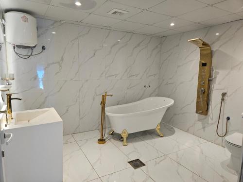 Ḩajlahمنزل حجري بحديقتين的白色的浴室设有浴缸和卫生间。