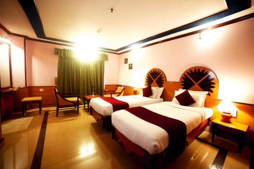 安加马尔伊The Surya, Cochin的酒店客房带两张床和一张桌子以及椅子。