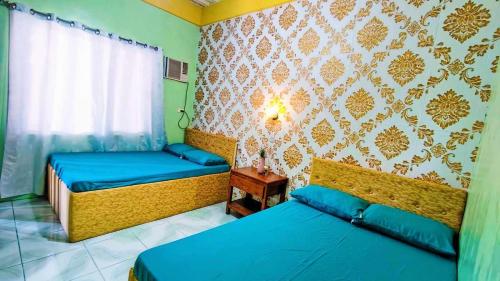 ZambalesEmshienell Beach Resort and Event Place的配有两张床的客房,设有绿色的墙壁和窗户
