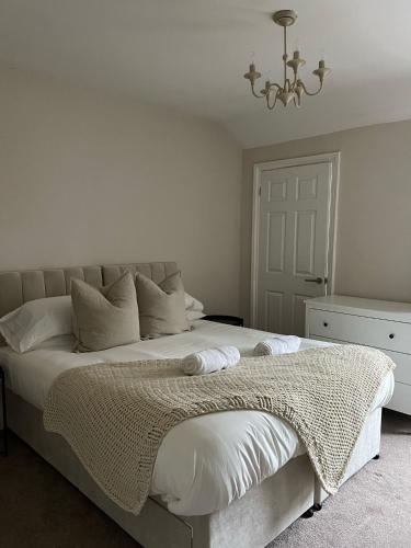 沃特福德Rickmansworth Lodge的白色卧室配有一张带吊灯的大床