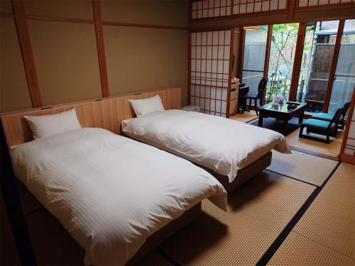 由布市汤布院山田日式旅馆的配有一张桌子和一把椅子的客房内的两张床