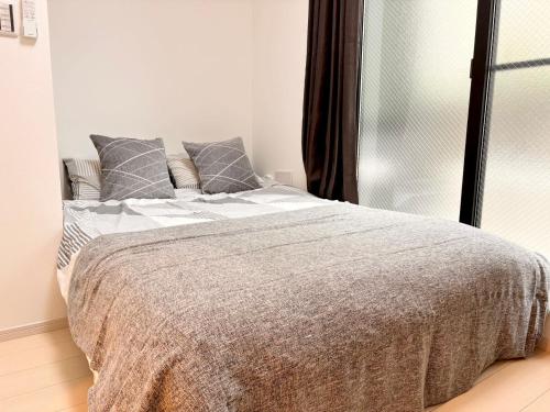 东京IXO Ts1的白色卧室配有带灰色枕头的床