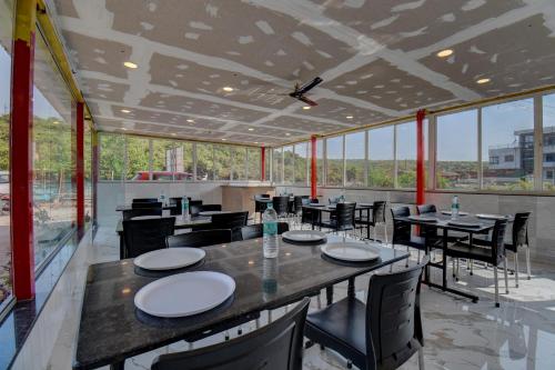 马哈巴莱斯赫瓦尔The Greenpark Retreat, Mahabaleshwar的餐厅设有桌椅和大窗户。
