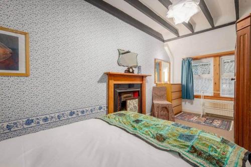 BoarhillsMill Cottage - Cosy & Quaint Cottage - 10 mins from St Andrews的一间卧室配有一张床和一个壁炉