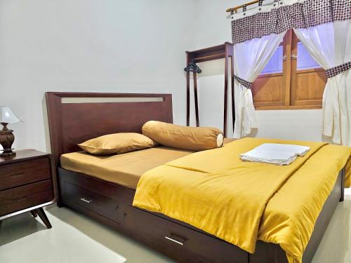 TimuranOmah Tabon Jogja - Dekat Dengan Malioboro的一间卧室配有一张带黄色床单的床和一扇窗户。