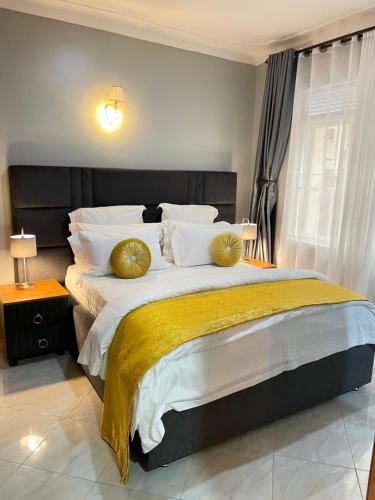 坎帕拉Athena Apartments的卧室配有带金色枕头的大床