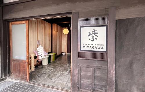 高山Hostel Miyagawa by Murasaki Ryokan的门上标有标志的建筑物入口