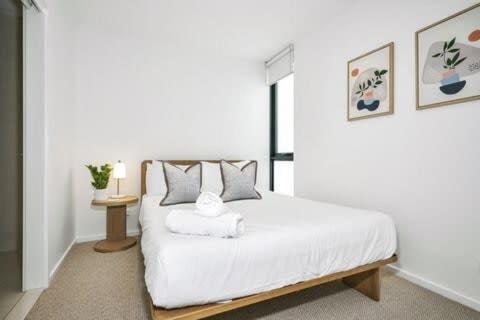 墨尔本Stylish Urban Retreat with Spectacular Views and Prime Location的卧室配有白色的床和桌子