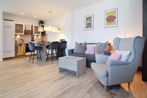 塞巴特阿尔贝克Haus Ahlbeck的一间带蓝色沙发的客厅和一间厨房