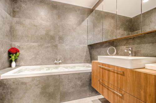 洛格沃Apartamenty Prezydenckie - Morski Szum - Alldayholiday的浴室配有盥洗盆和浴缸。