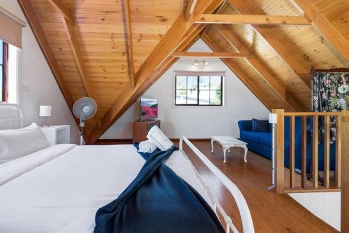 Malua BayMuwarra Cottage Malua Bay的卧室设有白色大床和木制天花板。