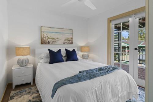 KarraganbahLake House Tuggerawong NSW的一间卧室配有一张带蓝色枕头的床和一扇窗户。