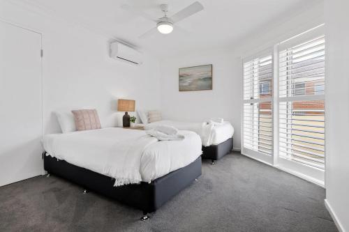 尼尔森湾Seashells Sweet Retreat - Luxury apartment的一间白色卧室,配有两张床和窗户