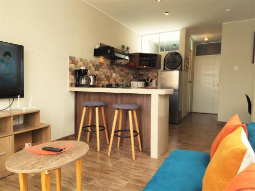 伊察Apartamento Hermoso en Residencial - Huacachina的厨房以及带2张凳子和1个柜台的起居室。