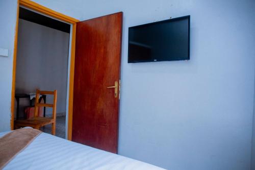 基加利SKYLIGHT MOTEL Airport Road的一间卧室配有一张床,墙上设有一台平面电视