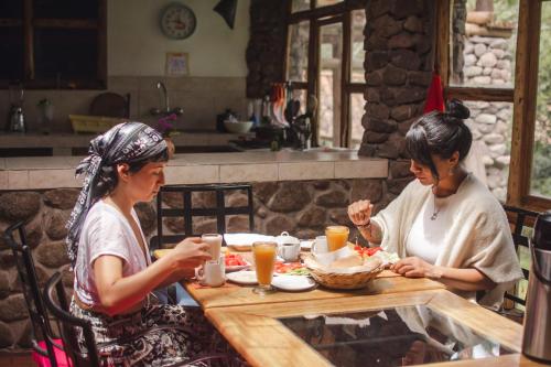 乌鲁班巴Logde Casa de campo & Retreat Center的两个坐在餐桌上吃食物的女人