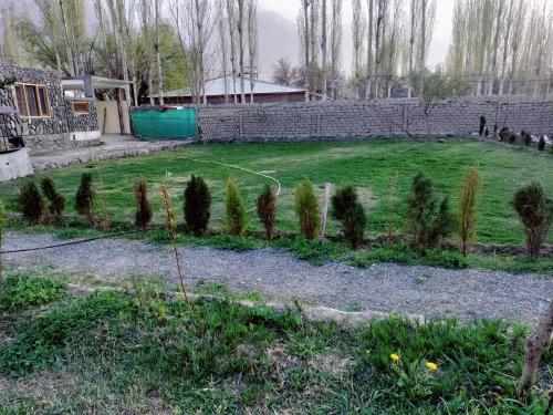 锡卡都Baltistan Sarayee hotel £ Guest House的一座种有树木和砖墙的花园