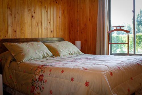 基利翁Cabañas Buenavista Quillón的木制客房的一张床位,设有窗户