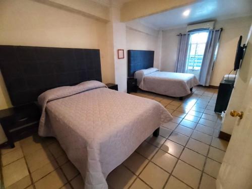 San Juan Bautista TuxtepecHotel Fragata的酒店客房设有两张床和窗户。