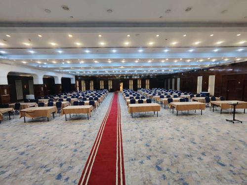 巴格达Almansour Hotel的一个带椅子和红地毯的大型宴会厅