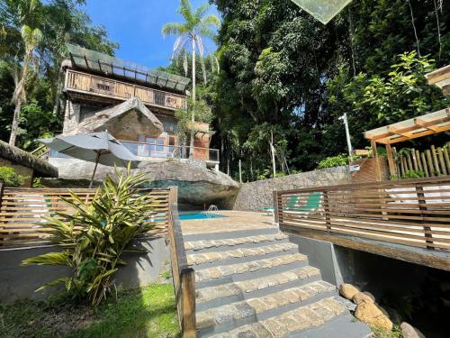 伊利亚贝拉Yannai Chalé Praia的一个带楼梯和遮阳伞的游泳池的度假酒店