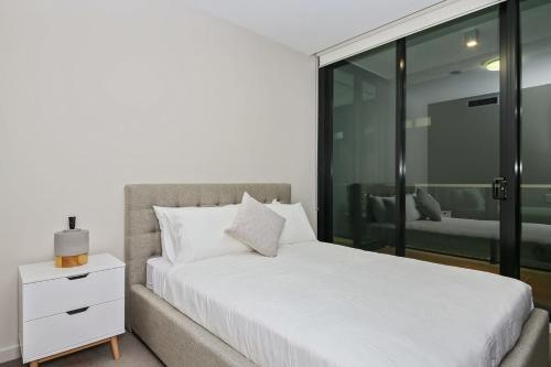 墨尔本A Comfy Albert Park Apt Next to Grand Prix Circuit的卧室配有白色的床和窗户。